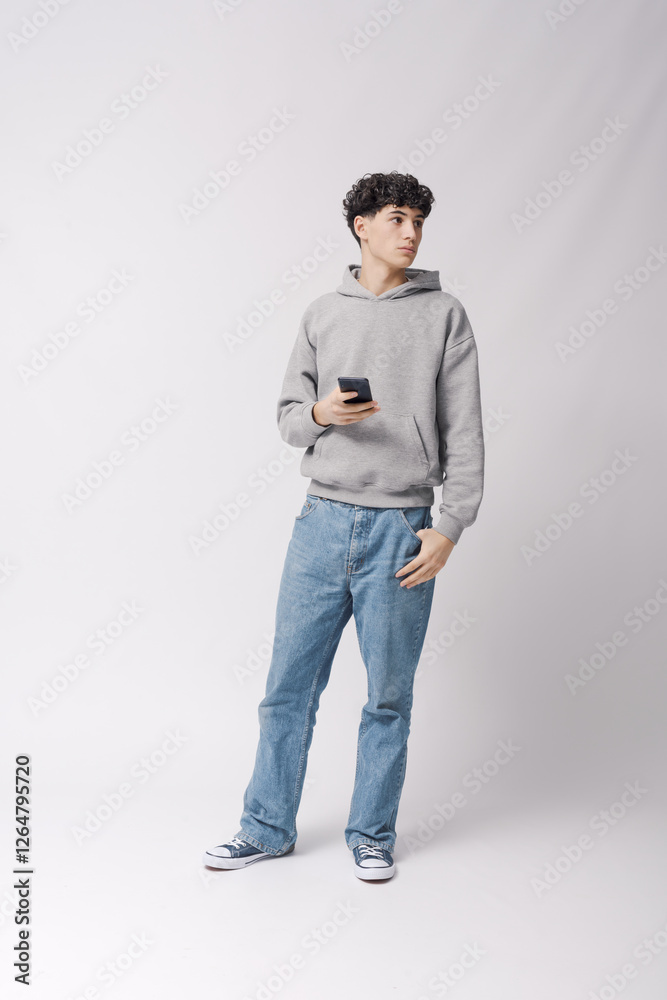 Naklejka premium Teenager holding his smartphone and standing