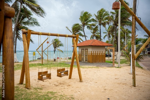 Fototapeta Naklejka Na Ścianę i Meble -  Wooden swings on a tropical beach with palm trees and ocean view.