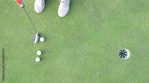 A person is putting and training with a golf club and golf balls.