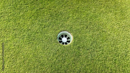 A person is standing on a golf course, holding a golf club and preparing to hit a golf ball
