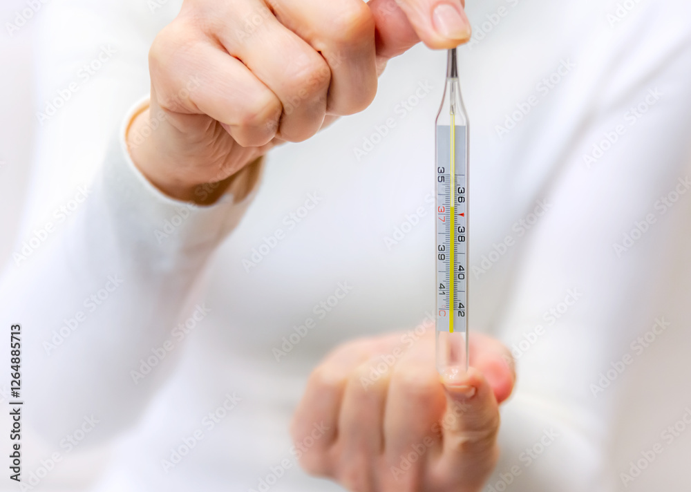 Holding a thermometer to check for fever during a home health assessment in bright indoor lighting Holding a thermometer to check for fever during a home health assessment in bright indoor lighting