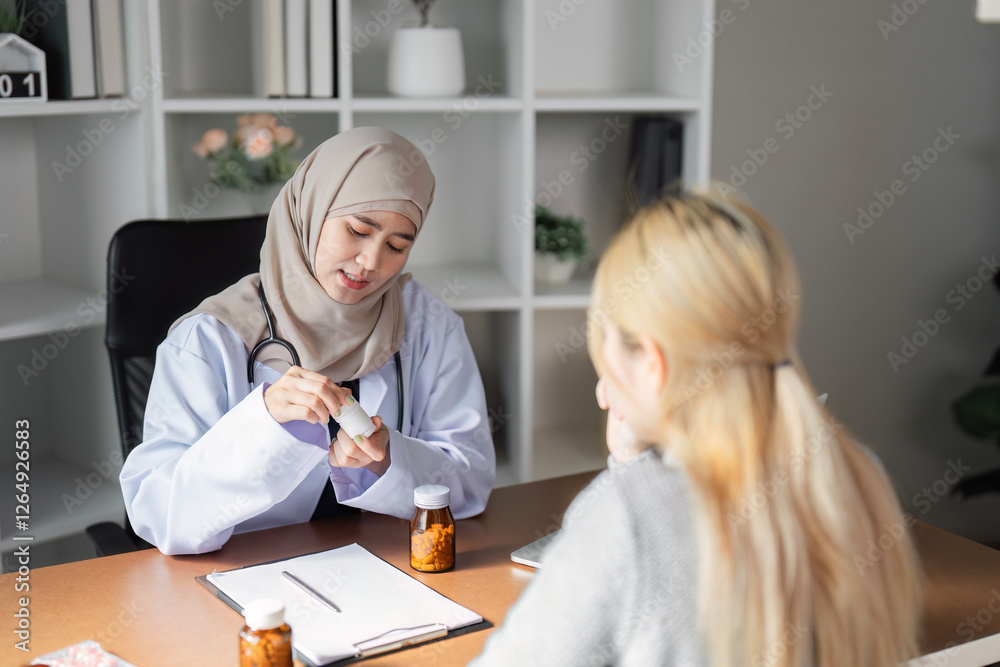 Obraz premium Caring female doctor in hijab explaining medication instructions to a patient in her office.