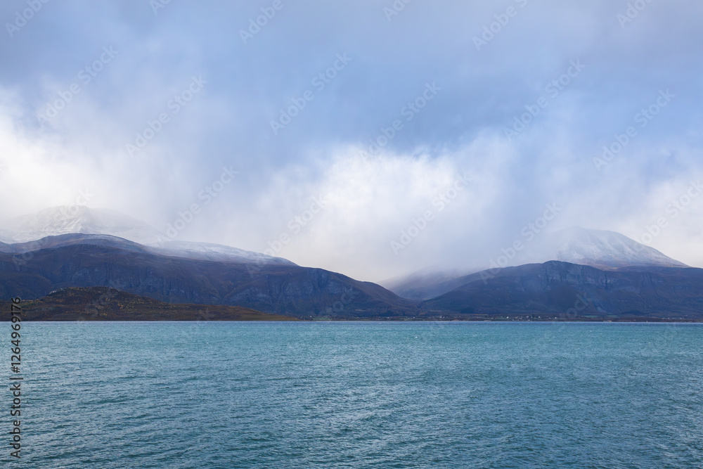Autumn landscape of the Lyngen Alps in Northern Norway with snowy peaks, dramatic clouds, and a tranquil fjord. Autumn landscape of the Lyngen Alps in Northern Norway with snowy peaks, dramatic clouds, and a tranquil fjord.