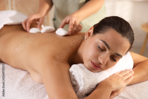 Woman receiving hot stone massage in spa salon photo