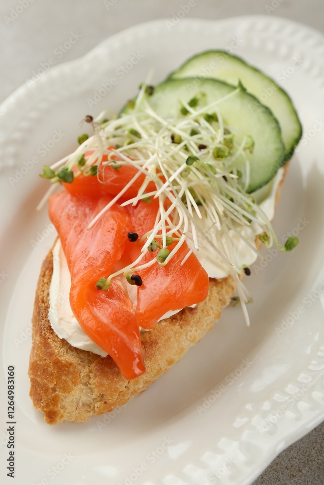 Delicious bruschetta with salmon, cream cheese and cucumber on light table, closeup