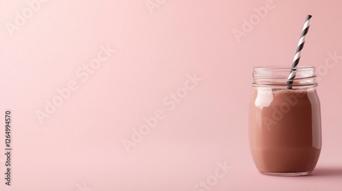 Glass jar with a black and white striped straw. the jar is filled with a dark brown liquid, which appears to be a smoothie or milkshake.