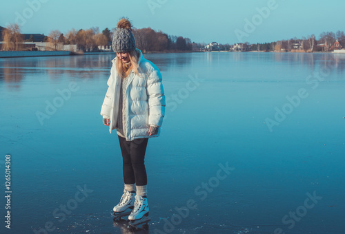 Woman learning to skate on ice in frozen lake, winter sport concept