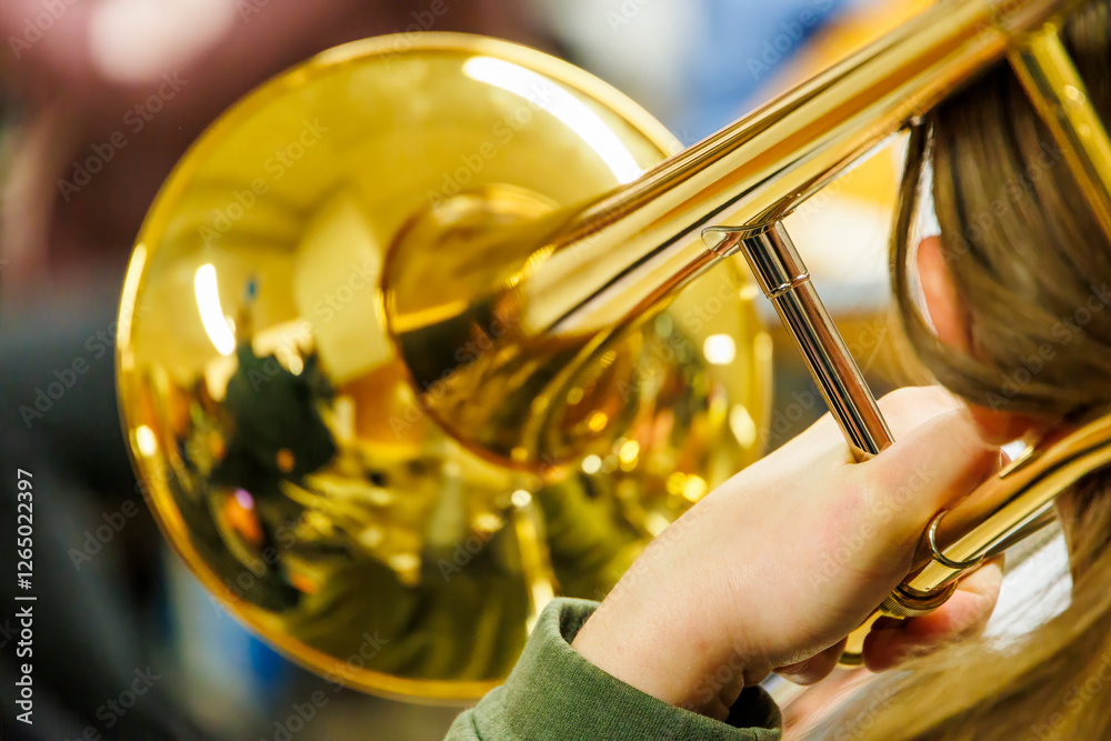 Obraz premium Trombone player with a golden brass instrument, close-up view with reflections on the bell