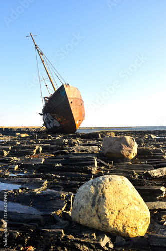 A fishing boat stranded on a rocky shore.