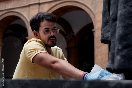 close-up of professional male art restorer cleaning on bronze statue with latex gloves