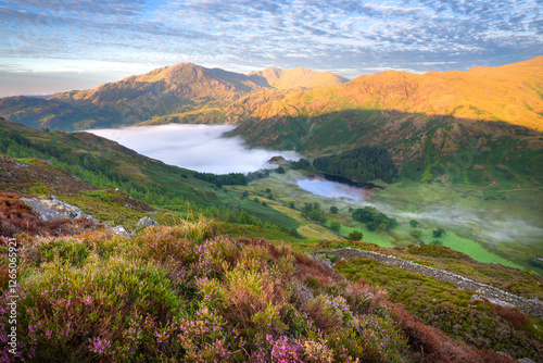 Golden morning sunlight on mountains with mist in the valley on a summer morning. Blea Tarn, Lake District, UK. photo