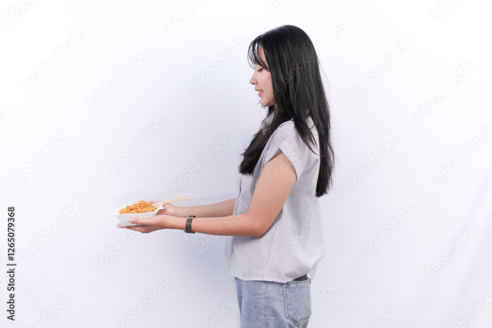 Indonesian Asian woman wearing grey shirt showing instant noodles in a container Indonesian Asian woman wearing grey shirt showing instant noodles in a container