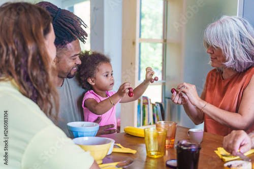 Foto Multigenerational family enjoying breakfast together at home, granddaughter inte