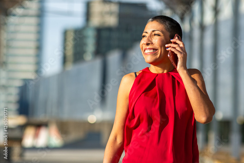 Portrait of a woman with short hair and red top talking on the phone in the city