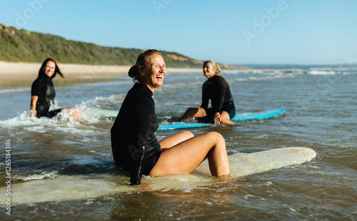 Female friends enjoying a surfing lesson at the coastline on a sunny day
