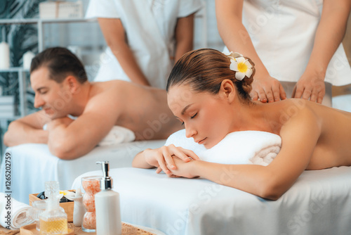 Caucasian couple customer enjoying relaxing anti-stress spa massage and pampering with beauty skin recreation leisure in day light ambient salon spa at luxury resort or hotel. Quiescent