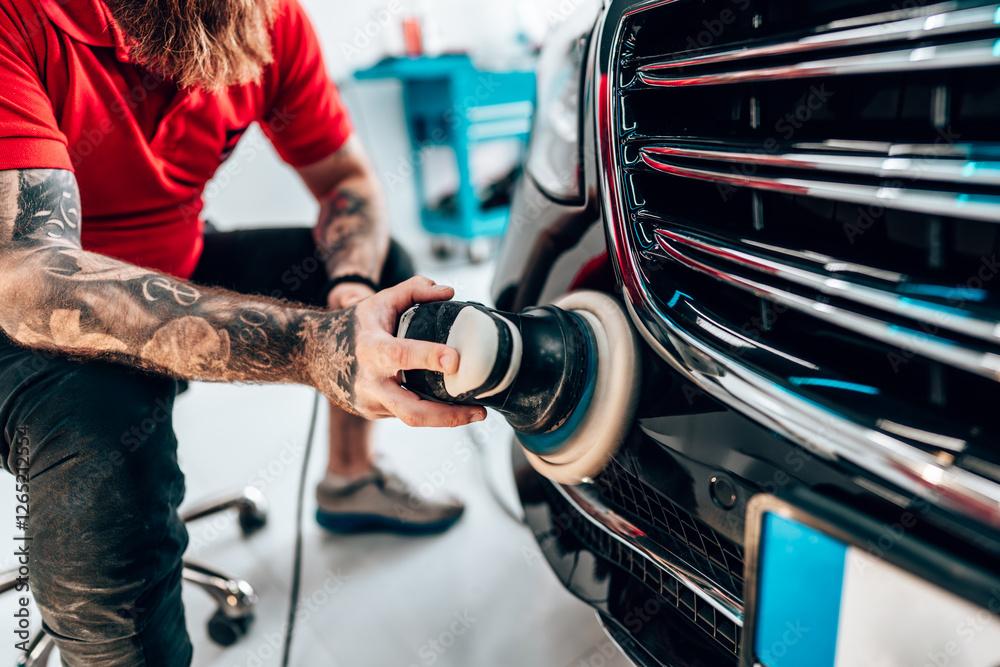 Obraz premium Professional vehicle polishing and detailing service in a modern car workshop. Brightly lit workspace with large led lights. High quality car valeting concept.