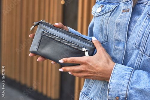 Obraz na płótnie Woman holding stylish leather wallet, denim jacket, outdoor, casual fashion, street style elegance, minimalist accessory concept w salonie