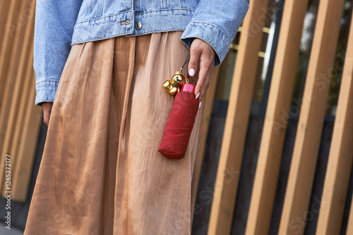 Obraz na płótnie Woman holding red umbrella, gold keychain, casual style, walking fashion, urban outfit, street look, denim jacket, modern elegance concept w salonie