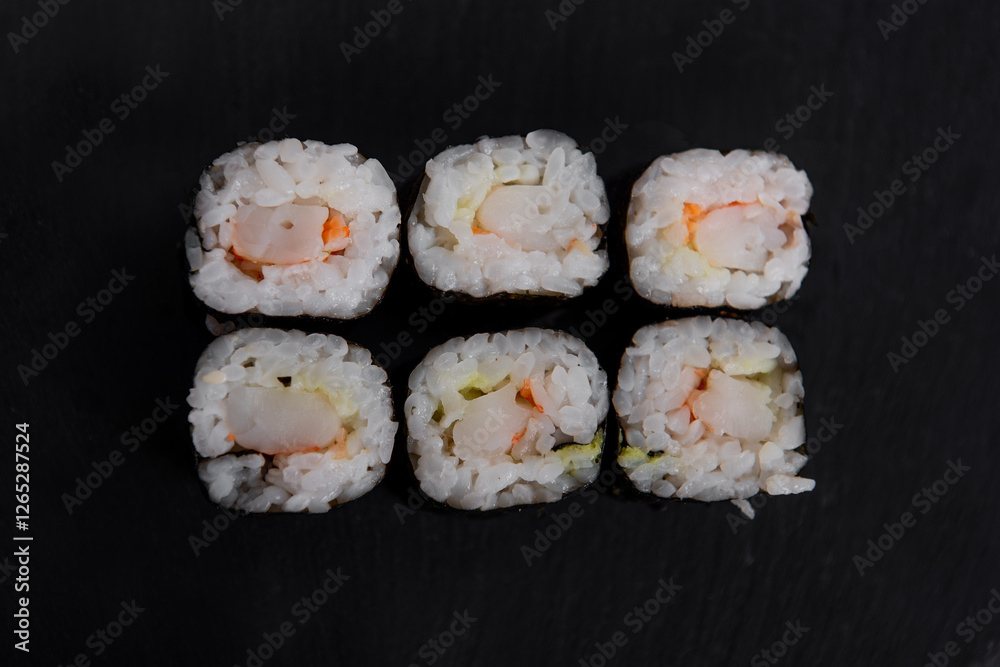 Top view of Six shrimp sushi maki rolls wrapped in nori, served on a black slate plate. A simple and elegant Japanese dish with fresh ingredients and delicate presentation. Top view of Six shrimp sushi maki rolls wrapped in nori, served on a black slate plate. A simple and elegant Japanese dish with fresh ingredients and delicate presentation.