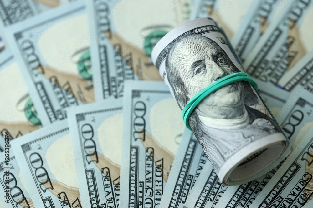 Roll of hundred dollar bills USD banknotes lies on big amount of united states money Roll of hundred dollar bills USD banknotes lies on big amount of united states money