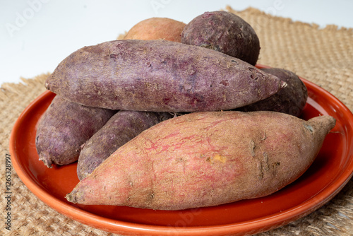 Colorful sweet-tasting tuberous roots vegetables purple and orange organic sweet potatos close up photo