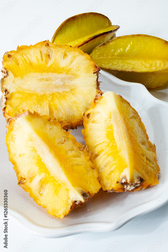 Two whole fresh ripe pineapples or sweet baby ananas and starfruits on white background close up Two whole fresh ripe pineapples or sweet baby ananas and starfruits on white background close up