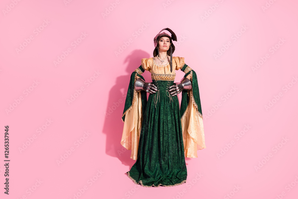 Elegant woman dressed as a medieval queen with knight armor hands against a pink backdrop Elegant woman dressed as a medieval queen with knight armor hands against a pink backdrop