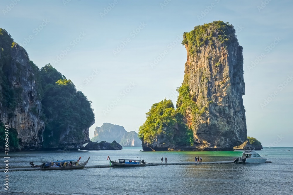 Tourists getting on boats with big rock in the background in Krabi, Thailand