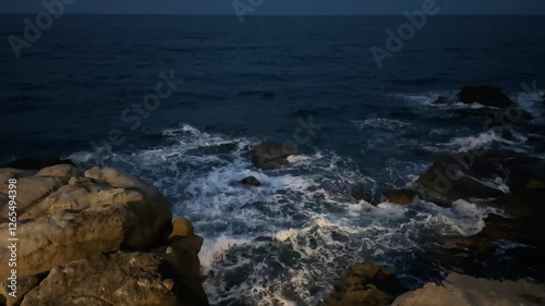 Rocky coast and sea surface with waves at night photo