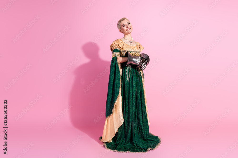 Fototapeta premium Elegant woman in historic attire and steel gloves on pink backdrop