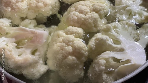 Cauliflower pieces in boiling water during their blanching in pot