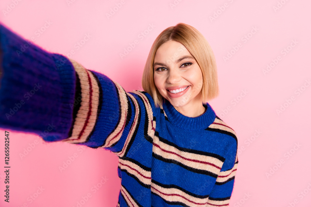 Smiling young woman in a stylish striped sweater posing with a cheerful expression against a vibrant pink background Smiling young woman in a stylish striped sweater posing with a cheerful expression against a vibrant pink background