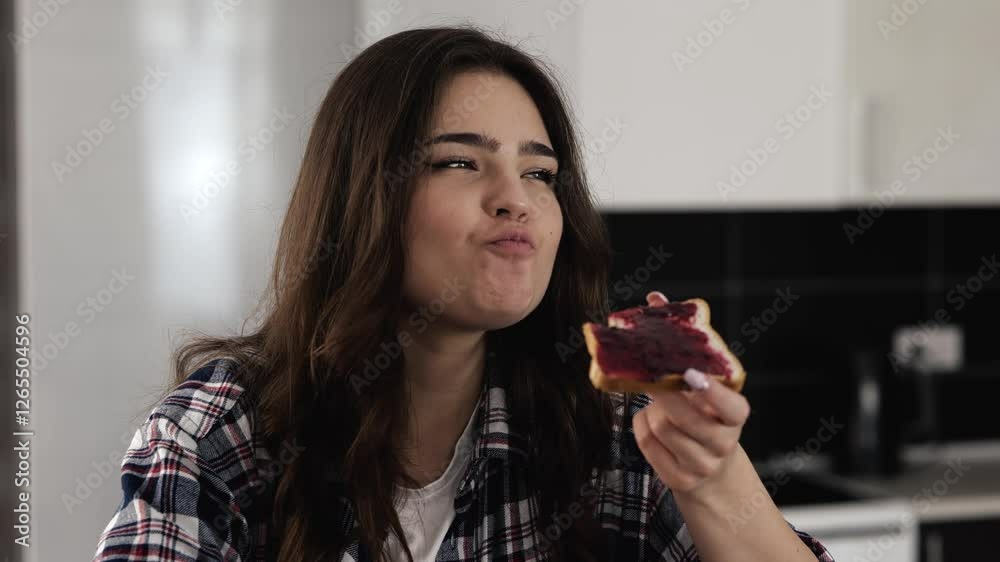 Young woman in kitchen during quarantine. Sit and eat tasty delicious piece of bread with jam. Enjoying meal breakfast in morning. Young woman in kitchen during quarantine. Sit and eat tasty delicious piece of bread with jam. Enjoying meal breakfast in morning.
