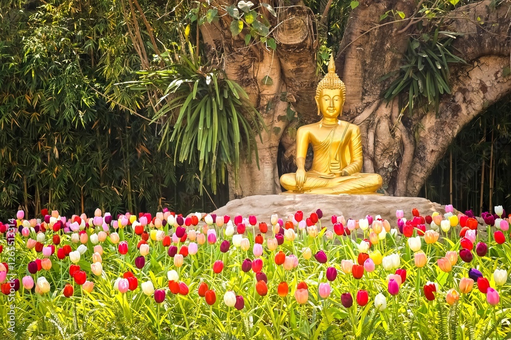 Golden statue of the Buddha with tulip flowers in Bangkok, Thailand