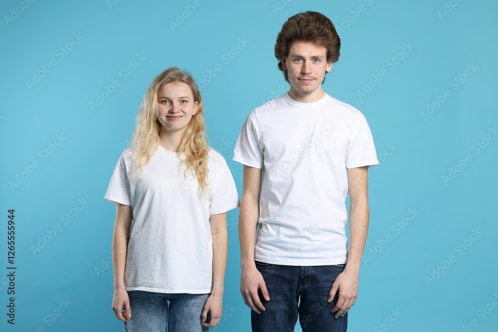 Fototapeta premium Young woman and man wearing blank white t-shirts on light blue background. Mockup for design