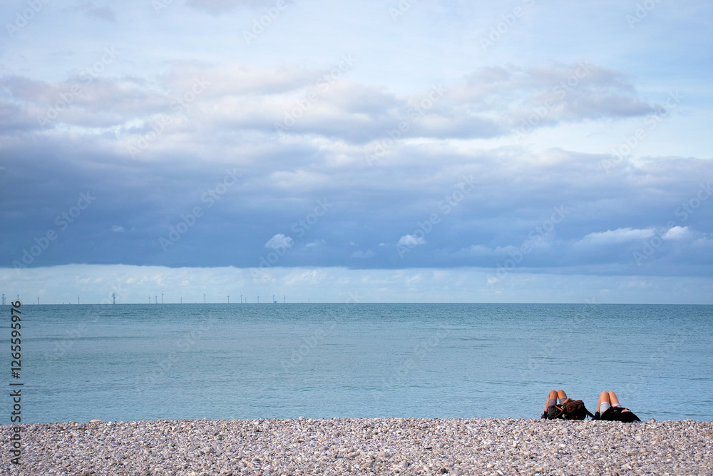 Entspannung am Strand von Yport. Kiesstrand mit dramatischem Himmel und Windpark am Horizont. Normandie, Frankreich Entspannung am Strand von Yport. Kiesstrand mit dramatischem Himmel und Windpark am Horizont. Normandie, Frankreich