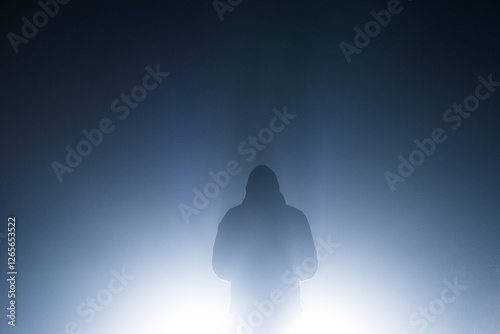 A sinister minimal figure of a hooded figure, silhouetted by glowing lights