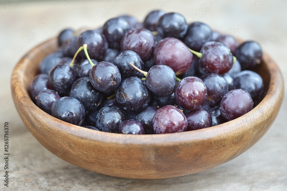 Freshly harvested dark grapes displayed in a rustic wooden bowl on a textured surface Freshly harvested dark grapes displayed in a rustic wooden bowl on a textured surface