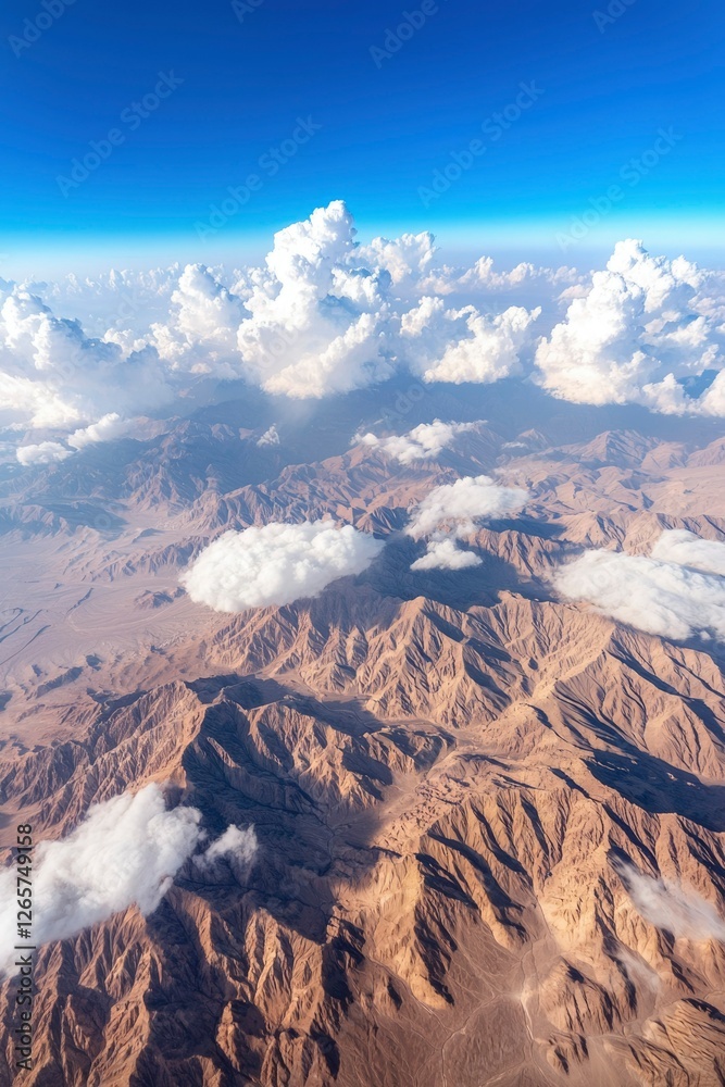 Fototapeta premium Aerial view of desert mountains, clouds, and blue sky; suitable for travel, tourism