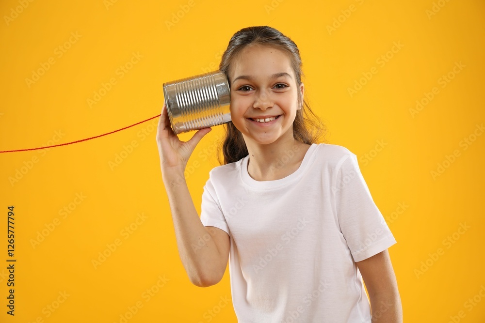 Girl using tin can telephone on yellow background Girl using tin can telephone on yellow background