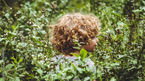 Child hiding in lush greenery, forest background, nature exploration