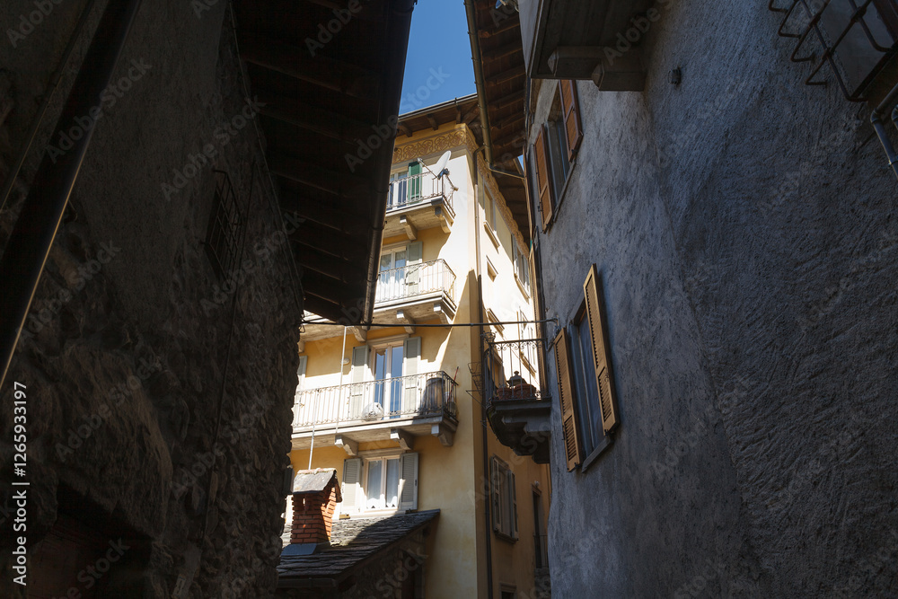 Street view of historical village Gromo, Bergamo, Lombardy, Italy. Narrow cobbled streets. Sun lights and shadows.