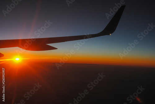 Airplane wing silhouette against a vibrant sunset sky photo