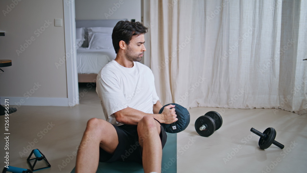 Obraz premium Sporty guy exercising mat twisting torso holding weighted bag. Athletic man