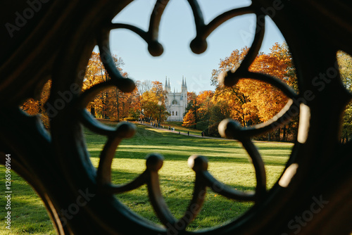 View of the autumn trees through the Gothic ornament of the ancient well, the Gothic church in the park. Autumn in a public park