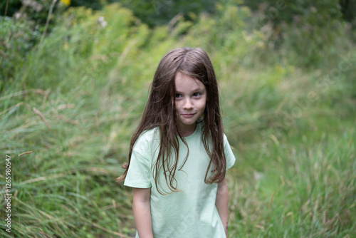 Little cute girl in a t-shirt  on a path in the middle of a summer forest. Concept of children's active travel in nature photo