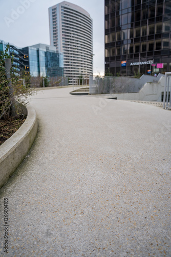 Urban walkway curves gently through modern architecture on a cloudy day