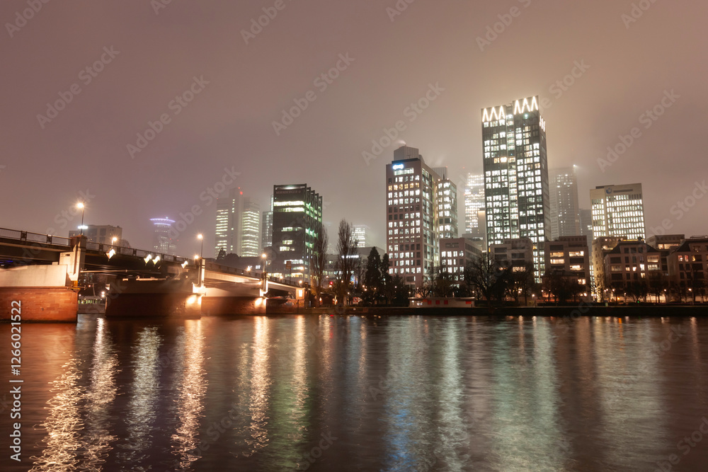 Modern cityscape with illuminated skyscrapers, bridge, and river at night Modern cityscape with illuminated skyscrapers, bridge, and river at night