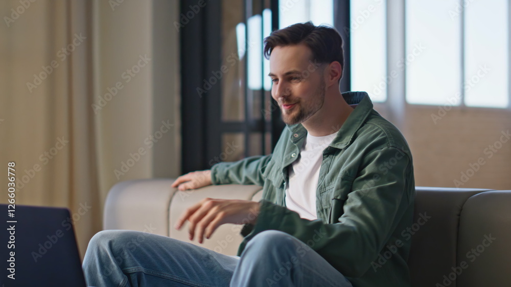 Happy hipster communicating laptop at couch closeup. Man talking video call Happy hipster communicating laptop at couch closeup. Man talking video call